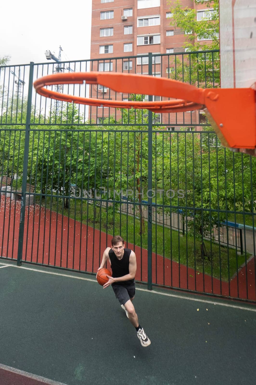 Caucasian man playing basketball outdoors. Vertical photo