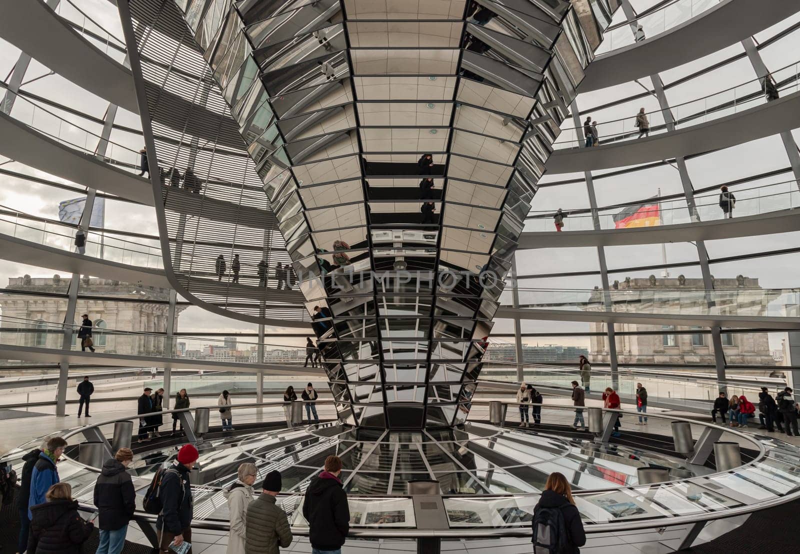 Berlin, Germany - Dec 20, 2023 - Several tourists visitor inside the futuristic glass dome of Reichstag building. Contemporary architecture of the Cupola of the Reichstag dome, a major tourist attraction of the berlin city, Space for text, Selective focus.