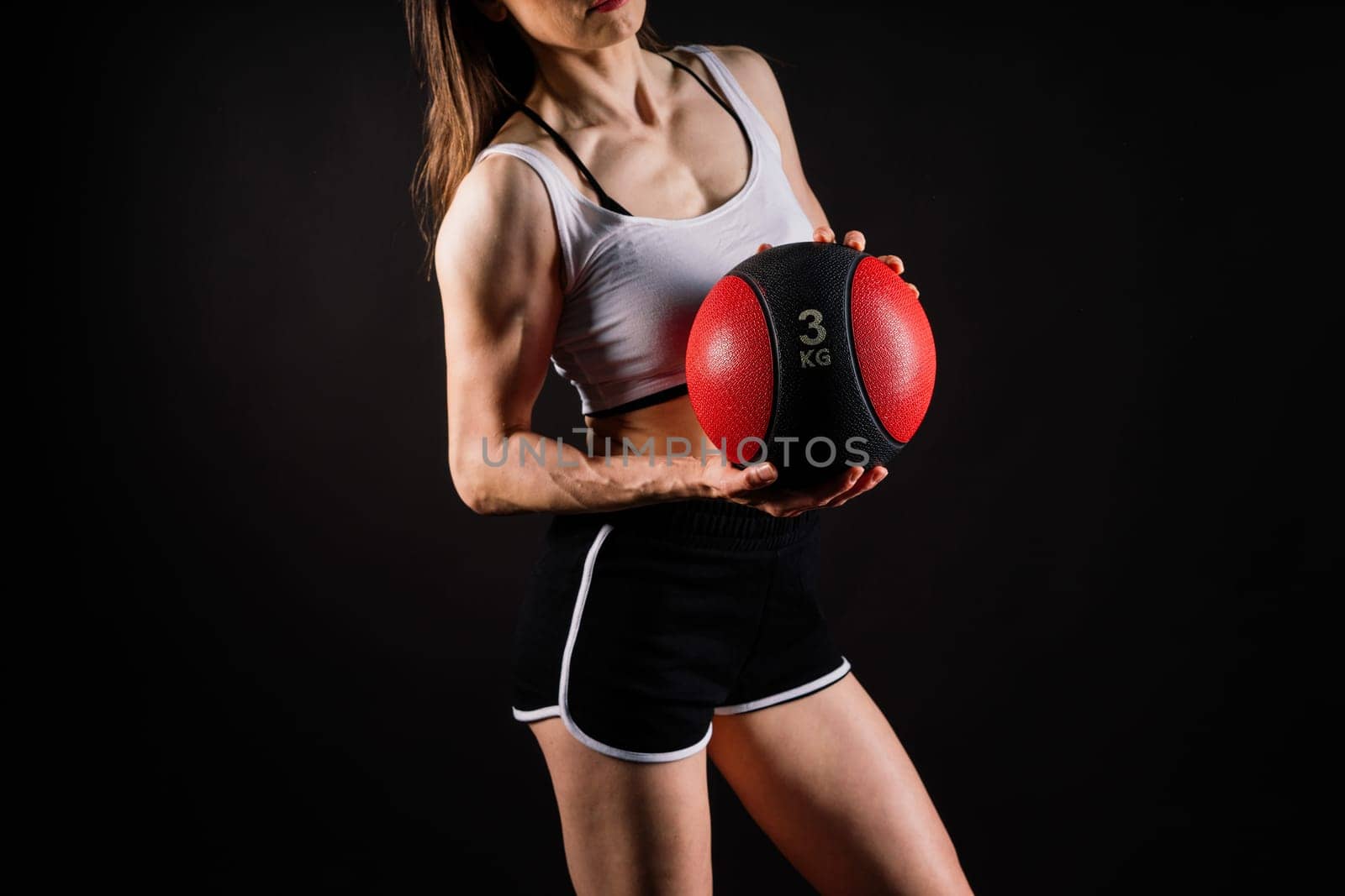 Portrait of a fitness happy fit woman standing holding a medicine ball. Copy Free space for text. Slim caucasian cross fit woman with fitness ball stand in gym, look. Plain light wall background