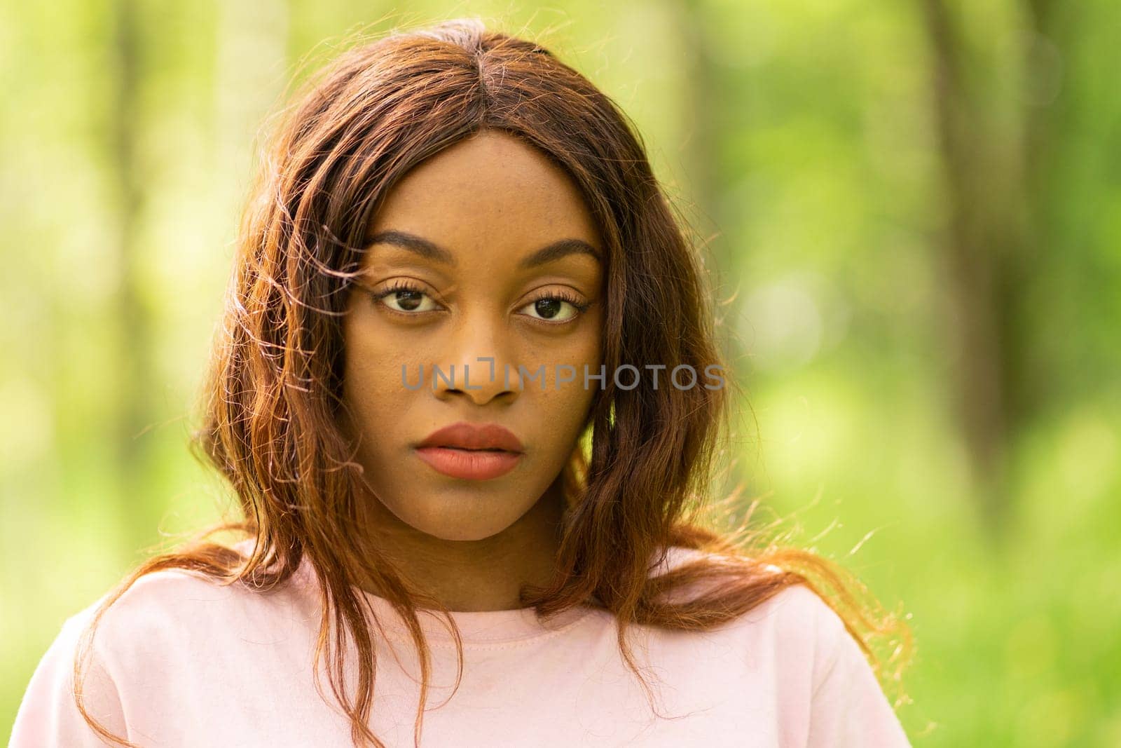 young black woman sitting on a bench in a park on a summer afternoon