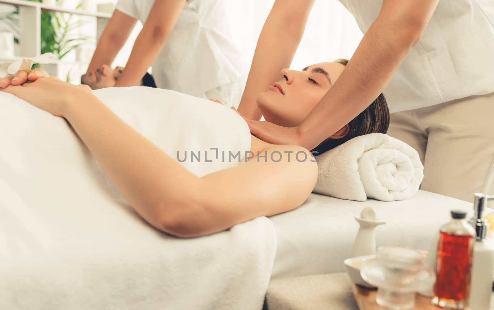 Caucasian couple customer enjoying relaxing anti-stress spa massage and pampering with beauty skin recreation leisure in day light ambient salon spa at luxury resort or hotel. Quiescent