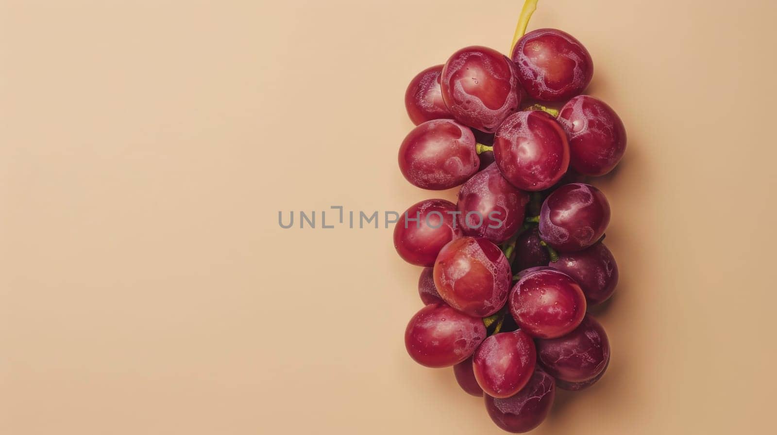Bunch of red grapes on a beige background, minimalistic fruit concept.