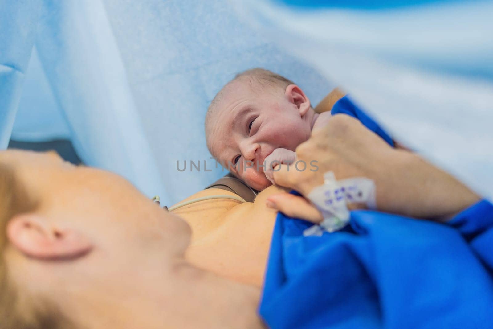 Baby on mother's chest immediately after birth in a hospital. The mother and newborn share a tender moment, emphasizing the bond and emotional connection. The medical staff ensures a safe and caring environment.