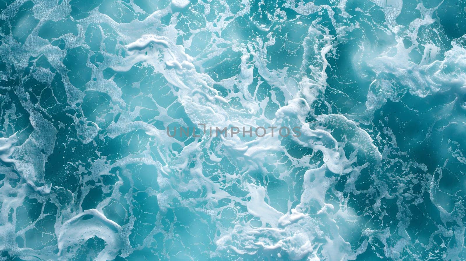 A closeup of electric blue waves with foam in a body of transparent water, showcasing a mesmerizing pattern created by the wind and ocean currents