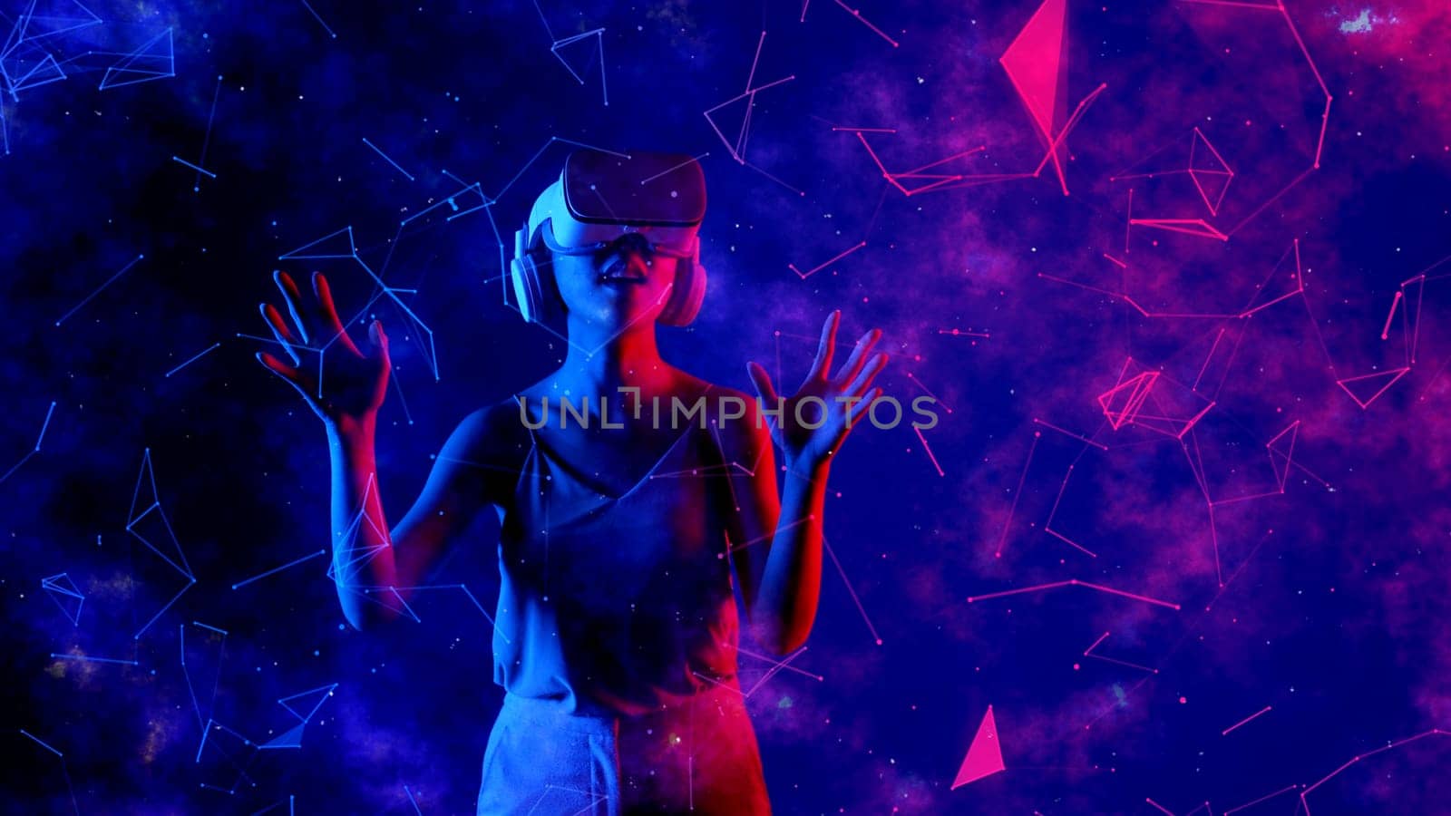 Excited smiling Asian woman looking around through VR metaverse with pointing on blue neon digital universe starry zodiac virtual space fantastic exploration nebula vibrant meta world. Hallucination.