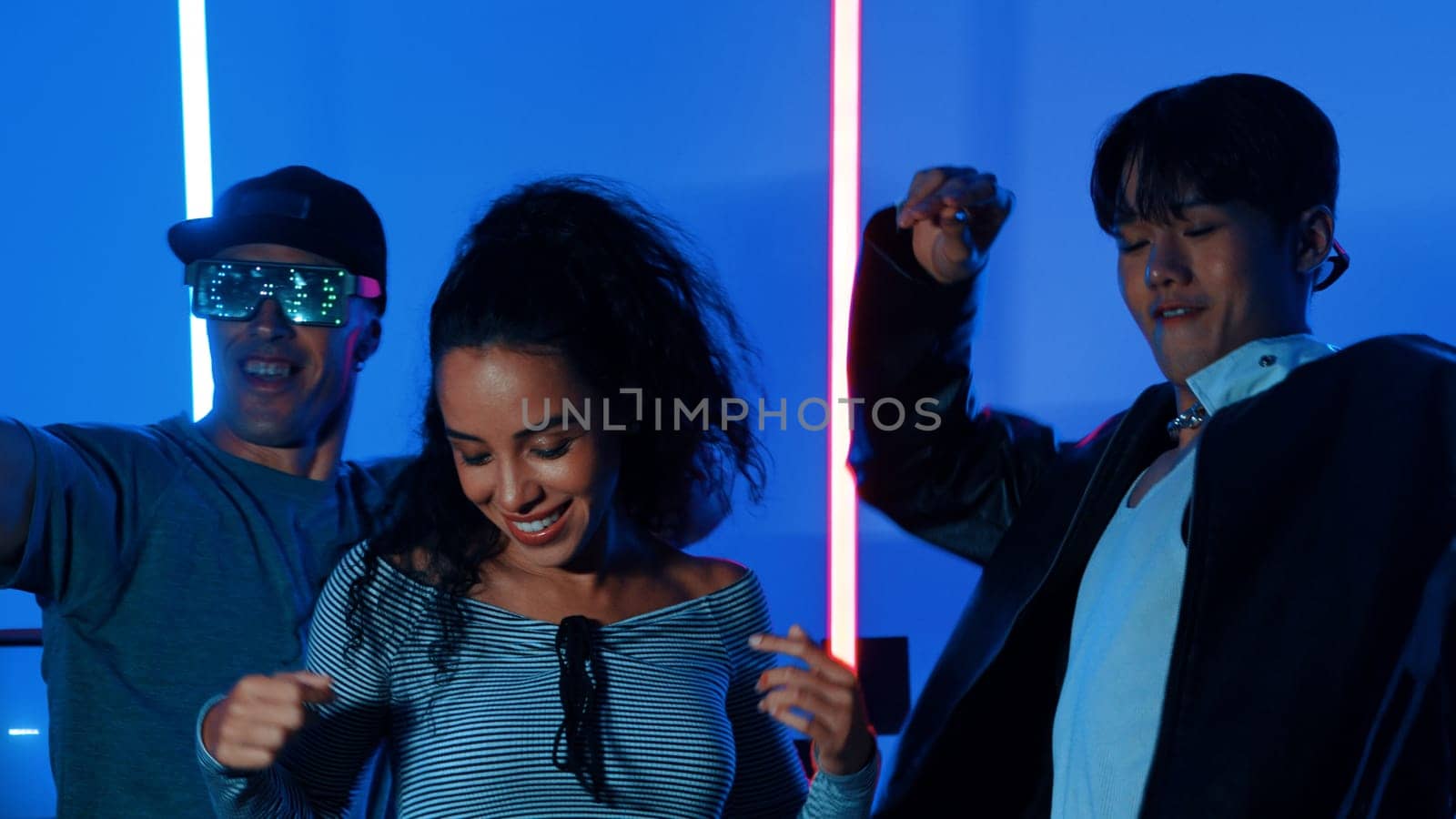 Happy hispanic girl with casual shirt dancing together with diverse break dancer with neon light. Professional street dancer moving to freestyle music with led light at house and party. Regalement.