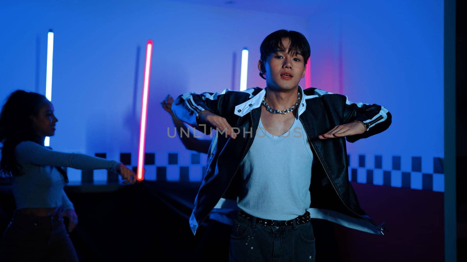 Skilled break dancer dancing in front of camera while diverse friend moving to pop or hip hop music behind. Attractive performer team taking turn to perform energetic movement at camera. Regalement.