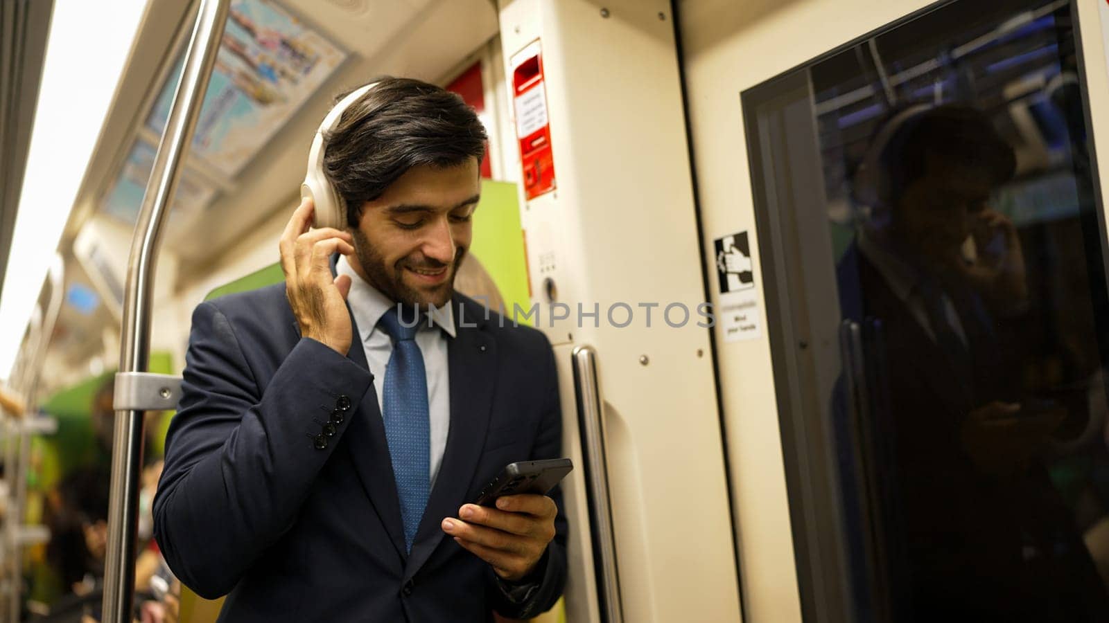 Smart executive manager wear headphone and listen music while standing in train. Professional business man lean at partition while listen relaxed song and choosing songs. Business concept. Exultant.