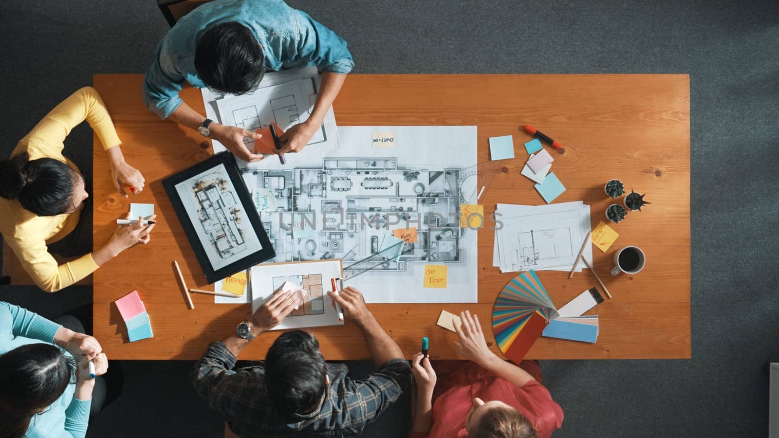 Top view of civil engineer writing and planning by using sticky notes to brainstorm idea. Top down aerial view of business people taking a note at table with project plans and equipments. Symposium.