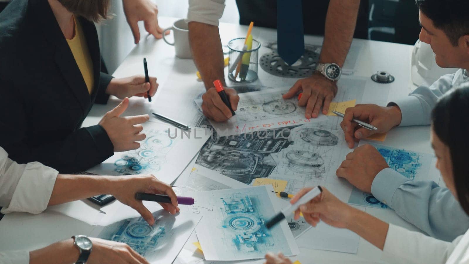 Top view of engineer pointing at turbine engine at meeting table with equipment. Aerial view of professional project manager talking and discussing about electronic generator system. Alimentation.