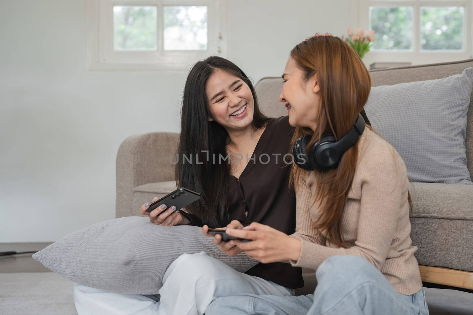 Two women share a joyful moment in a cozy living room, showcasing love and companionship in a contemporary home setting.