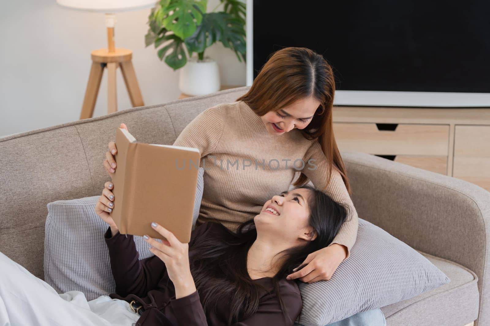 Lesbian Couple Enjoying Quality Time Reading Books Together at Home - LGBT Love and Relaxation by wichayada
