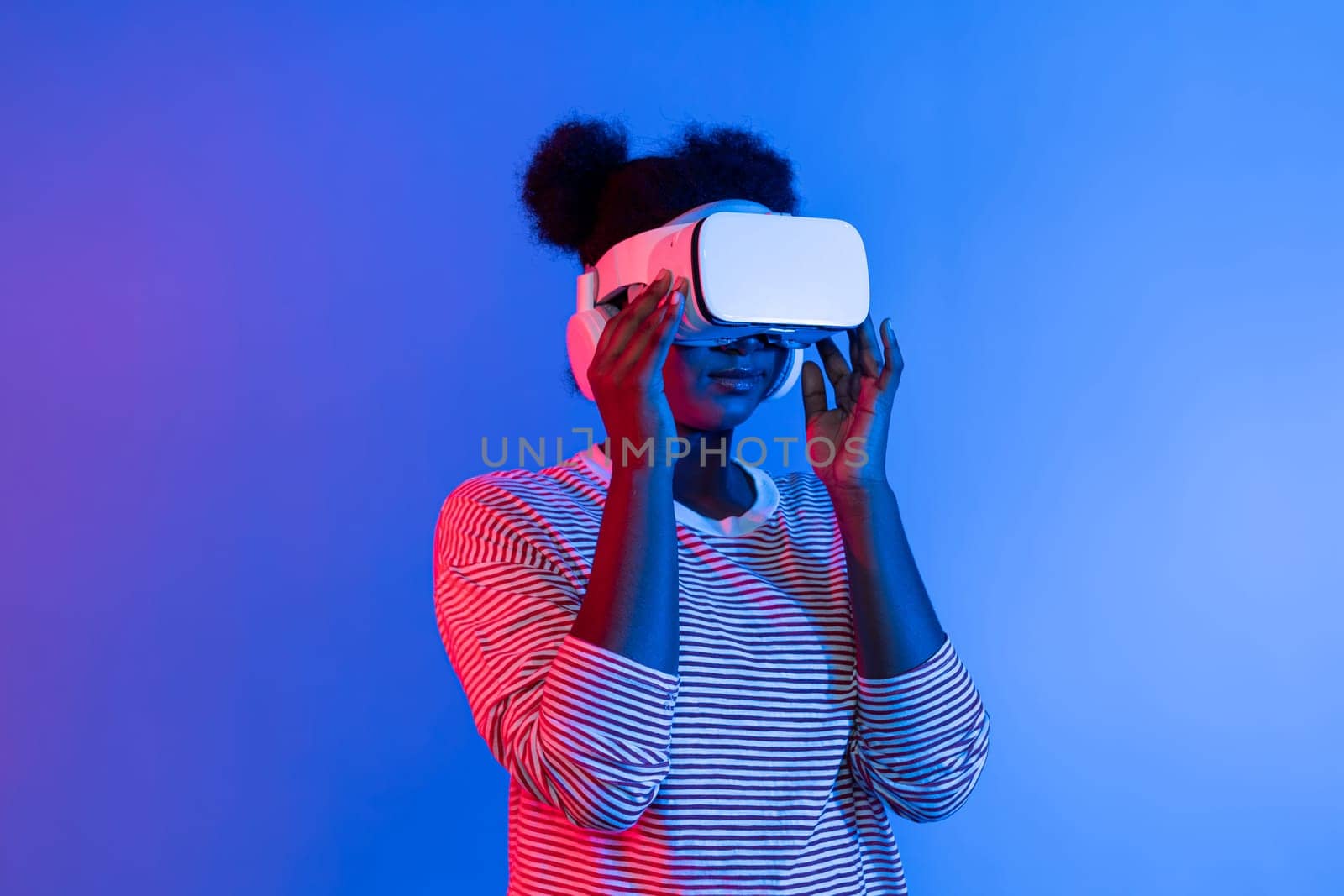 Young African woman with VR in presentation through metaverse study online neon studio lighting background in 3D technology innovation hologram technology application in user experience. Contrivance.