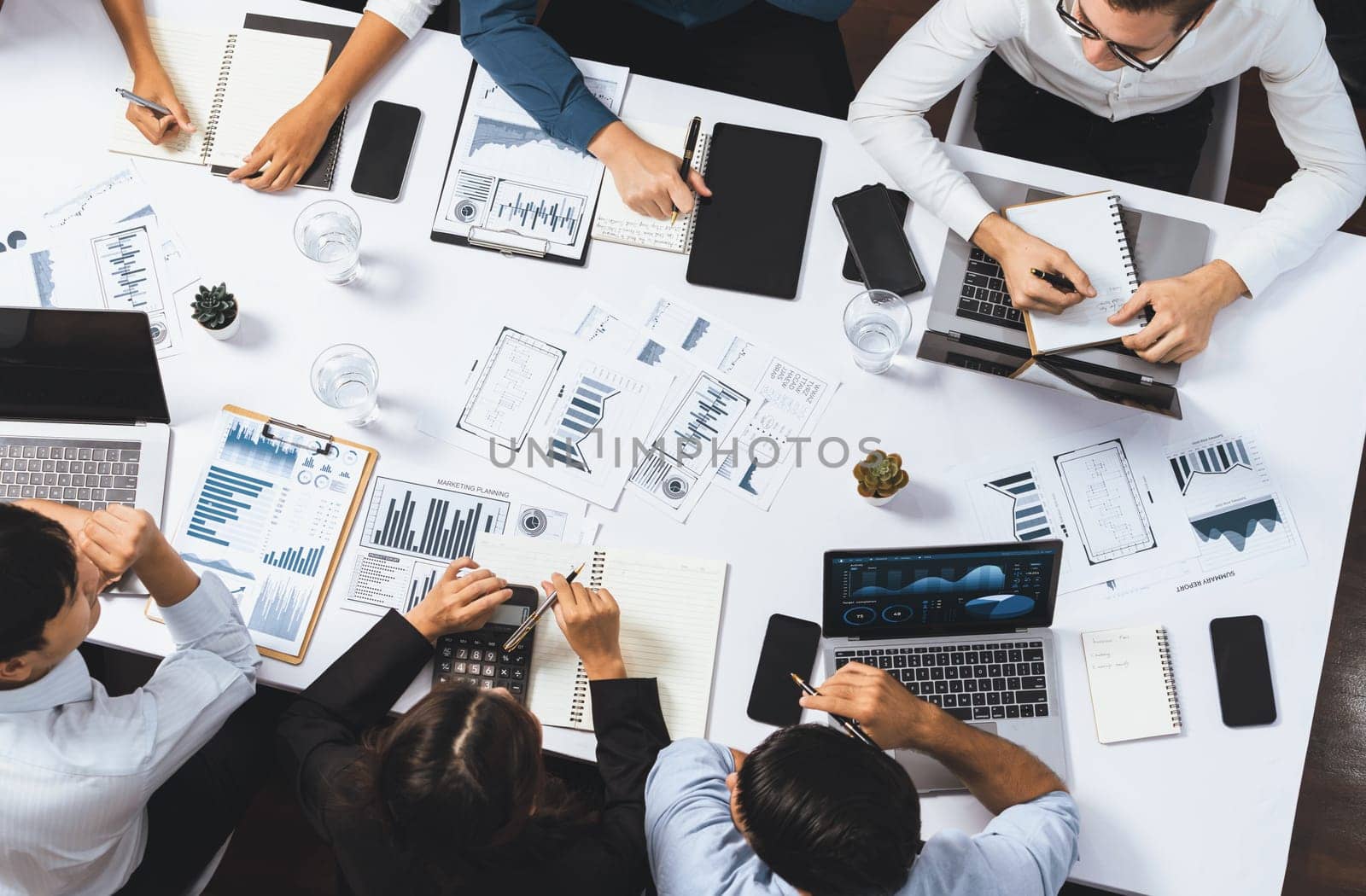 Top view analyst team utilizing BI Fintech to analyze financial data at table in meeting room. Analytic BI dashboard power on paper for business insight and strategic marketing planning. Prudent