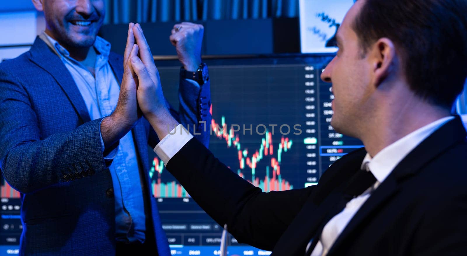 Cheerful two stock exchange traders giving high five for digital currency achievement on dynamic database background. Successful investors earning highest profit analyzed by market graph. Sellable.