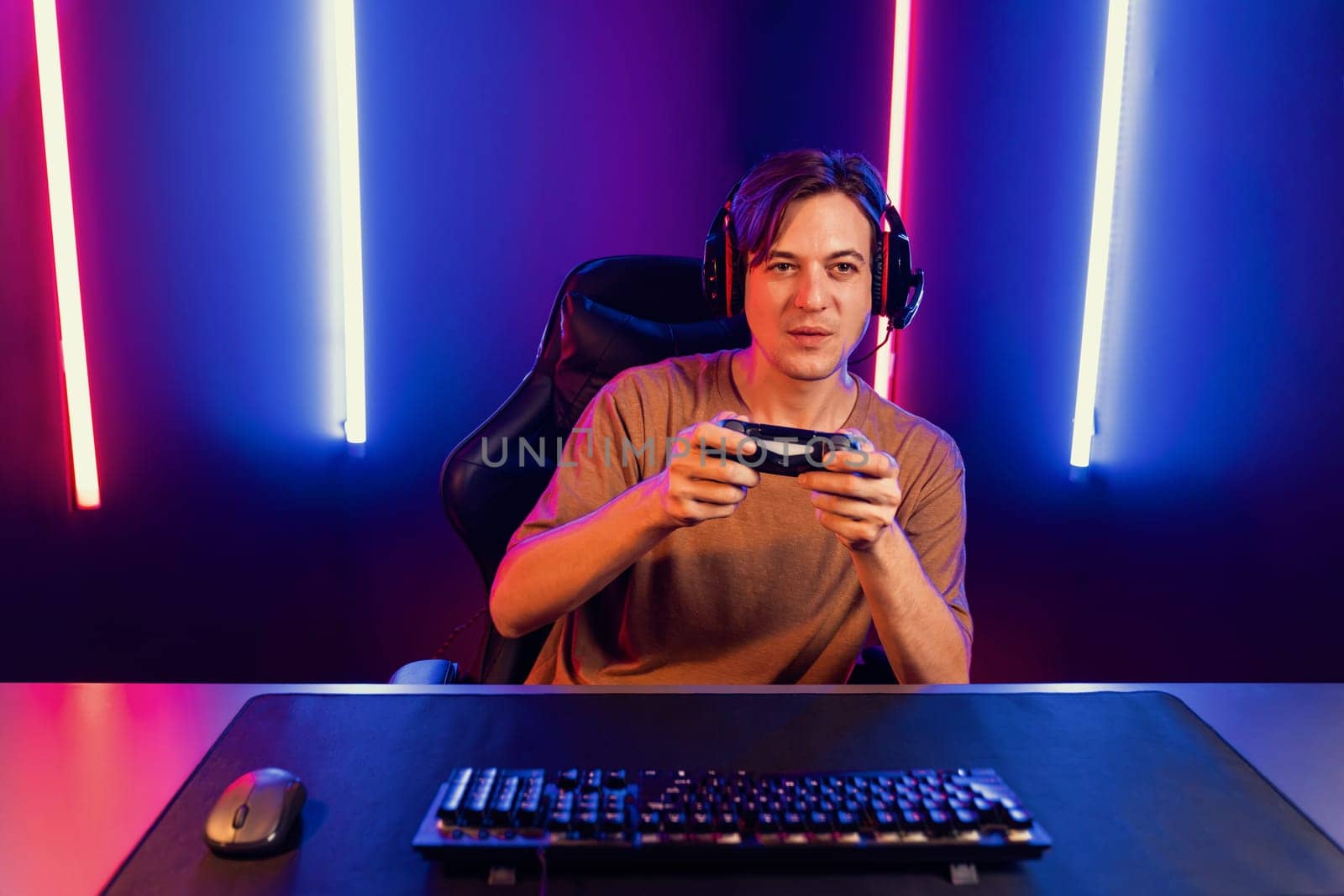 Enjoy smart gaming streamer with control joystick, playing game online of live streaming social media group with team skilled players on computer at modern technology cyber neon light room. Pecuniary.