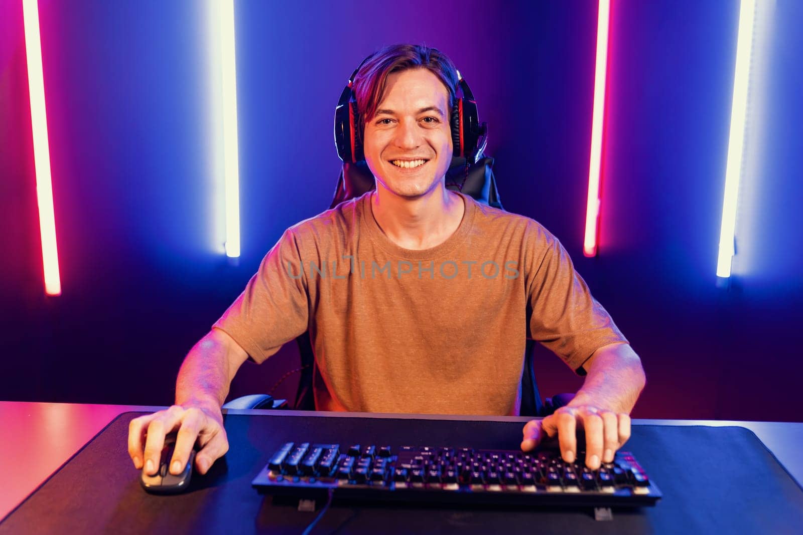 Host channel of gaming smart streamer playing online game to be winner, wearing headphone with viewers live steaming on media social online for selected team competition at neon light room. Pecuniary.