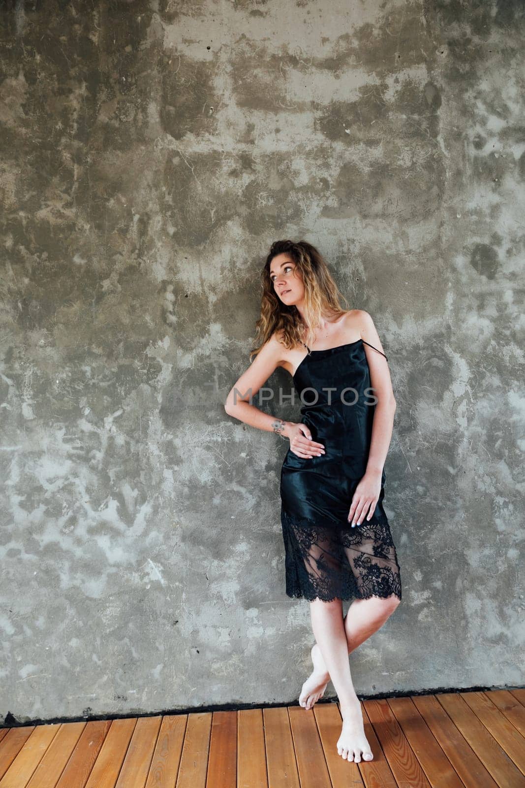 woman in a black dress posing against a wall in a room