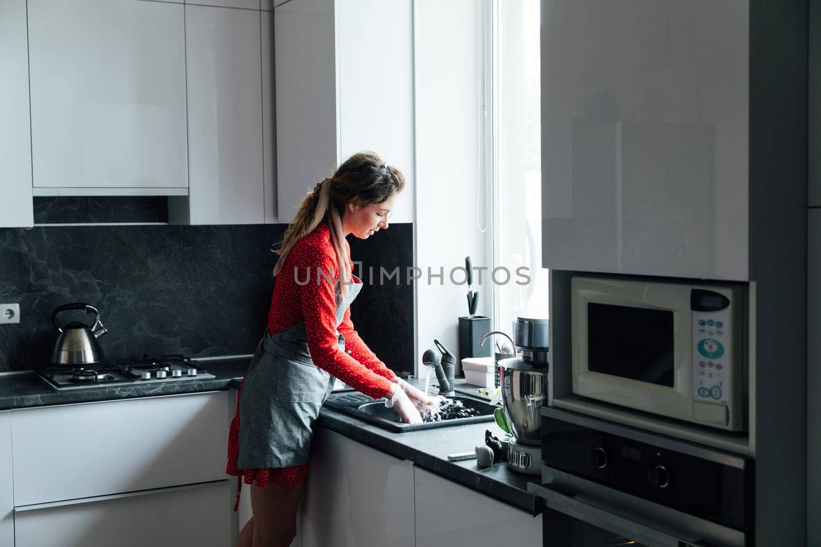woman washes dishes in the sink in the kitchen