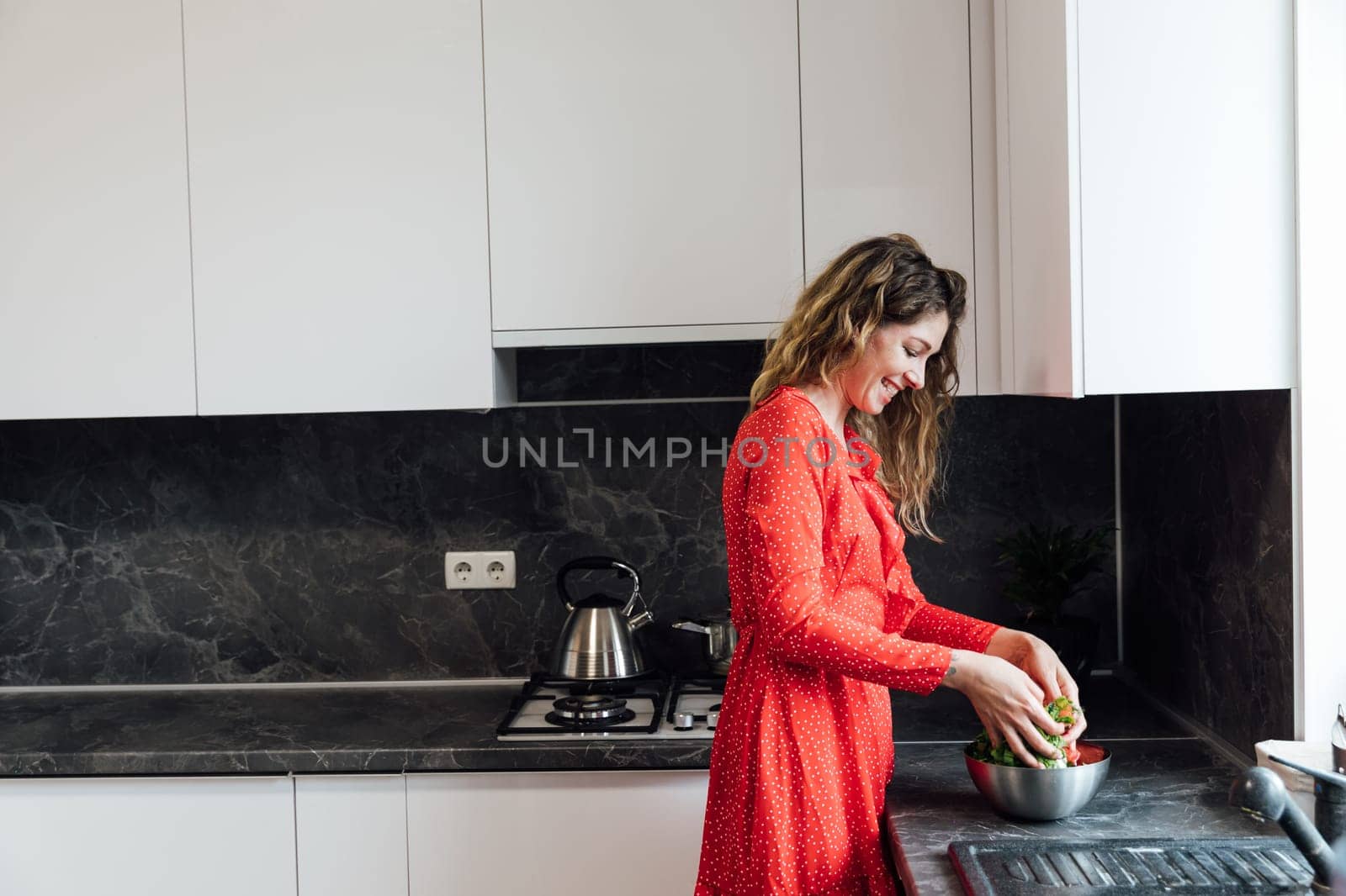 a woman in the kitchen interferes with her hands eating salad healthy food near the sink