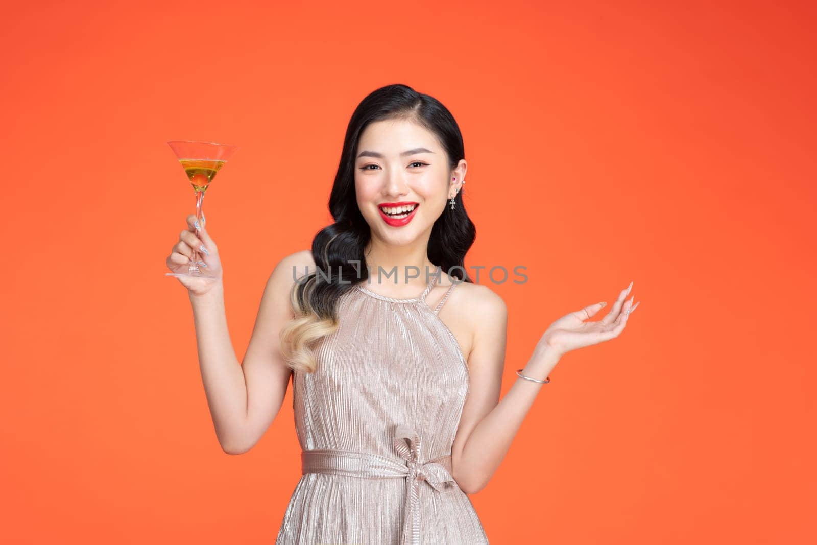 Portrait of attractive young festive asian offering a glass of champagne.