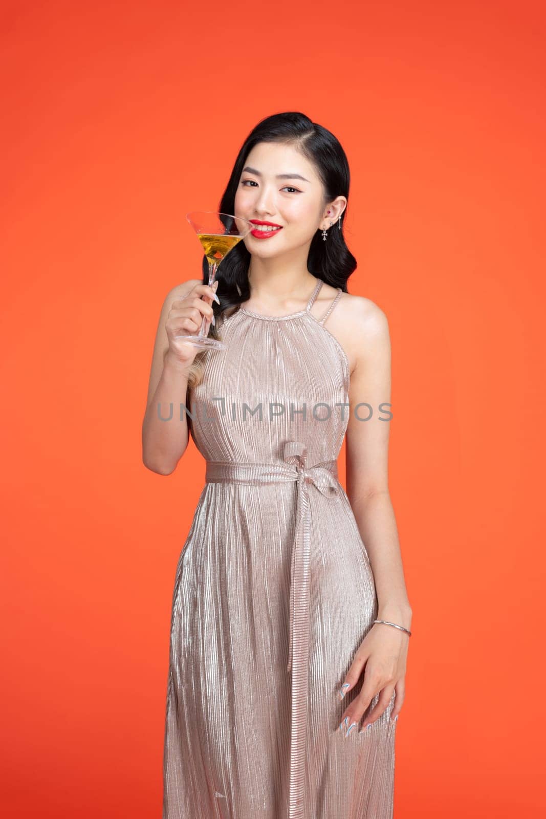 Woman, portrait smile and glass champagne standing in stylish fashion isolated on red background