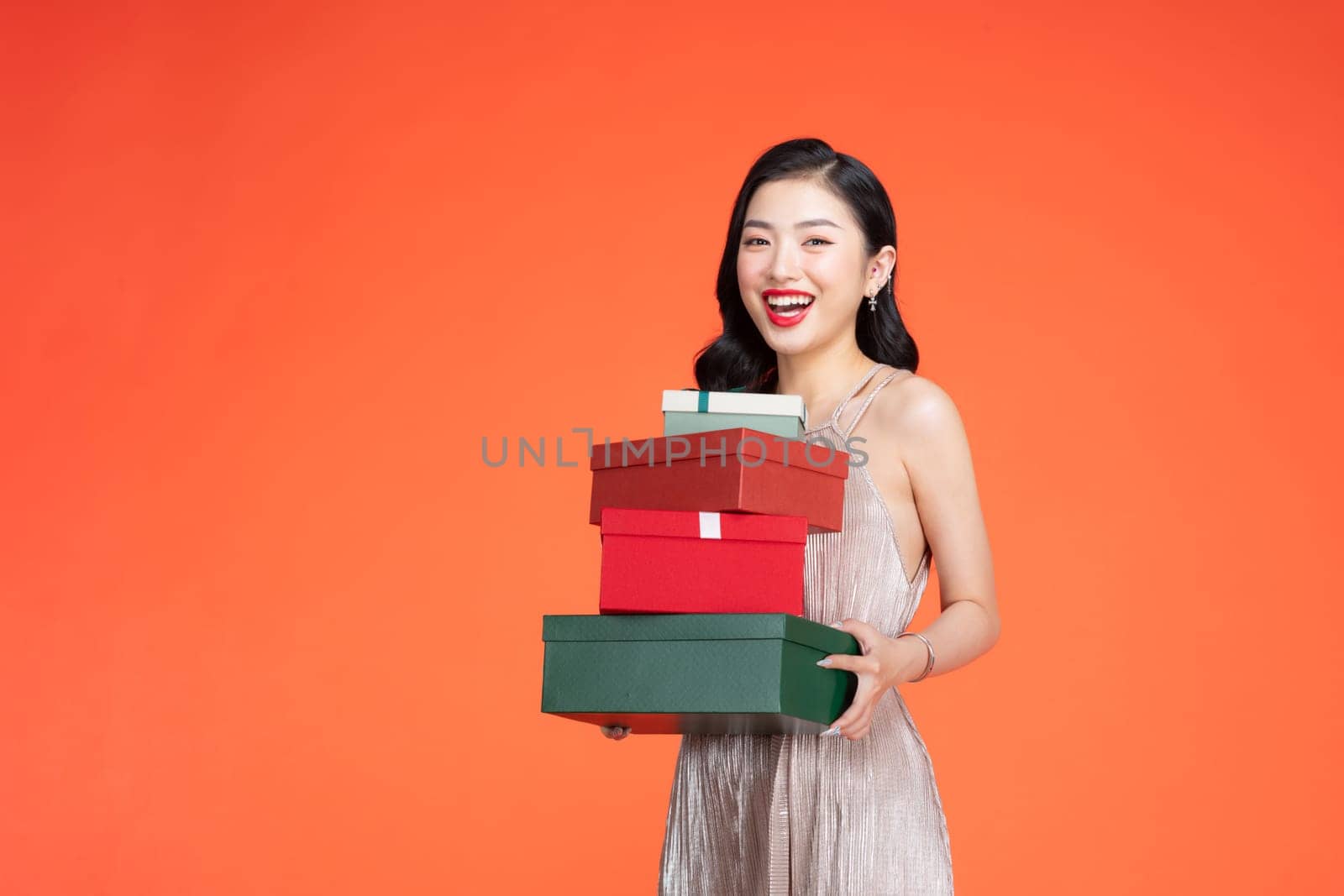 Portrait of stylish woman emotionally posing with present boxes over red background