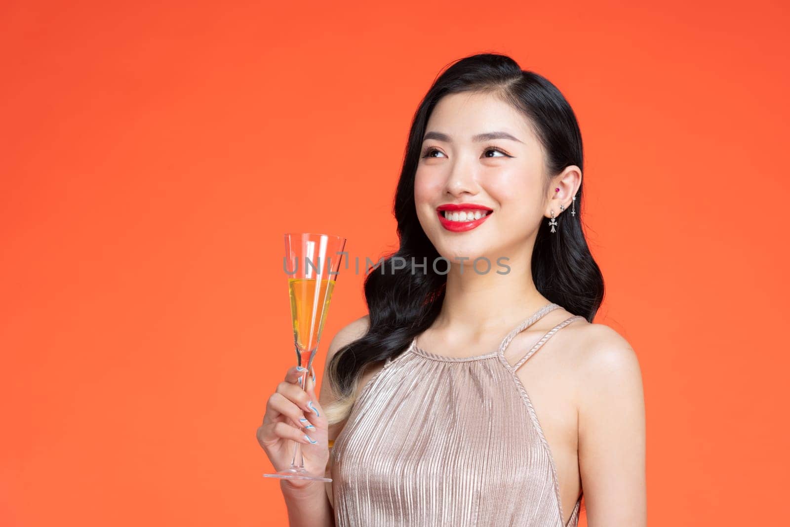 Young happy woman in shiny stylish dress looking away and smiling with champagne isolated