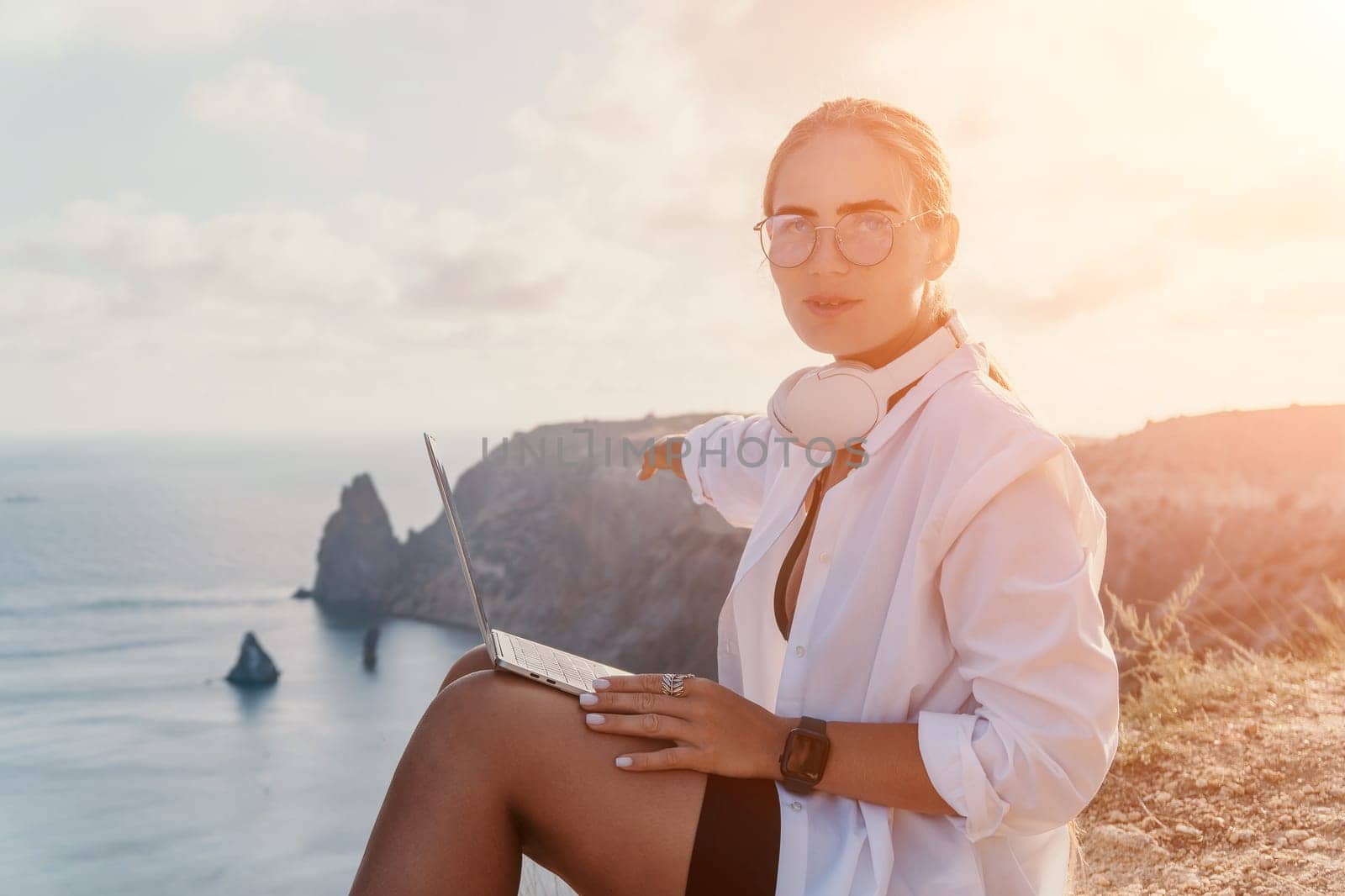 Woman sea laptop. Business woman, freelancer with laptop working over blue sea beach. Happy smiling girl relieves stress from work. Freelance, remote work on vacation, digital nomad, travel concept by panophotograph