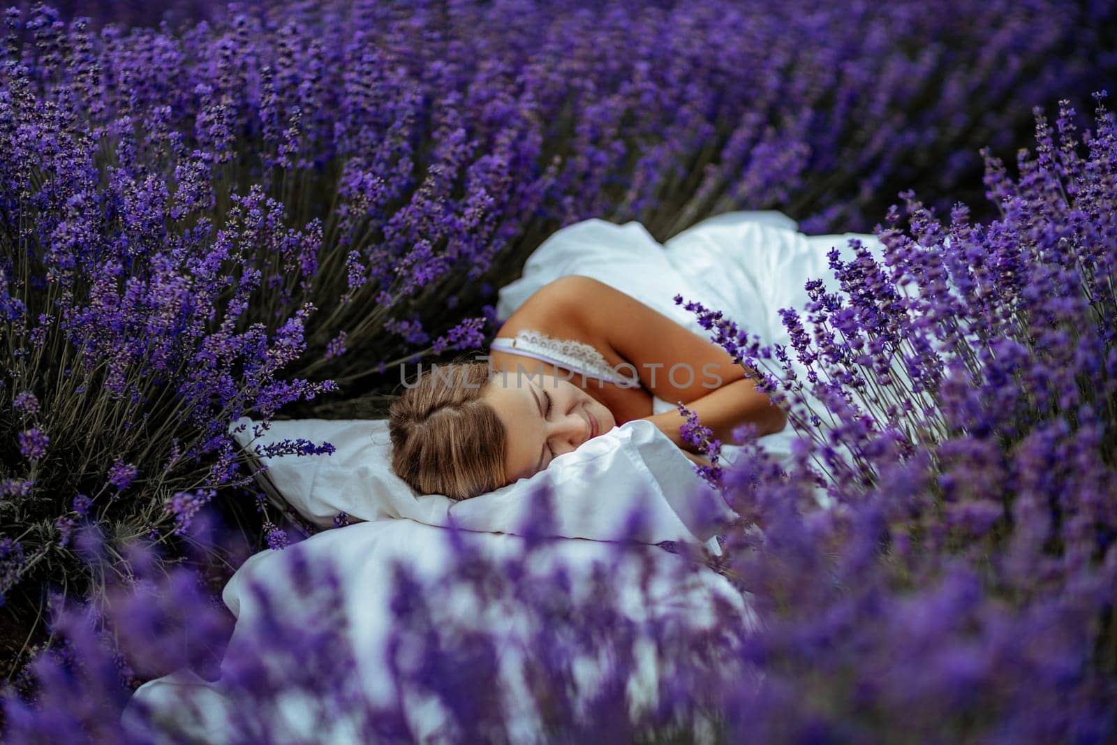 A middle-aged woman lies in a lavender field and enjoys aromatherapy. Aromatherapy concept, lavender oil, photo session in lavender by Matiunina