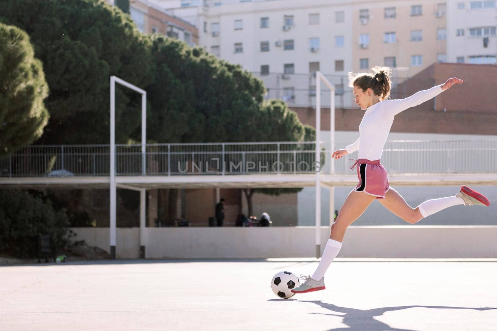 young caucasian woman kicking a soccer ball on an urban field, concept of sport and football lifestyle, copy space for text