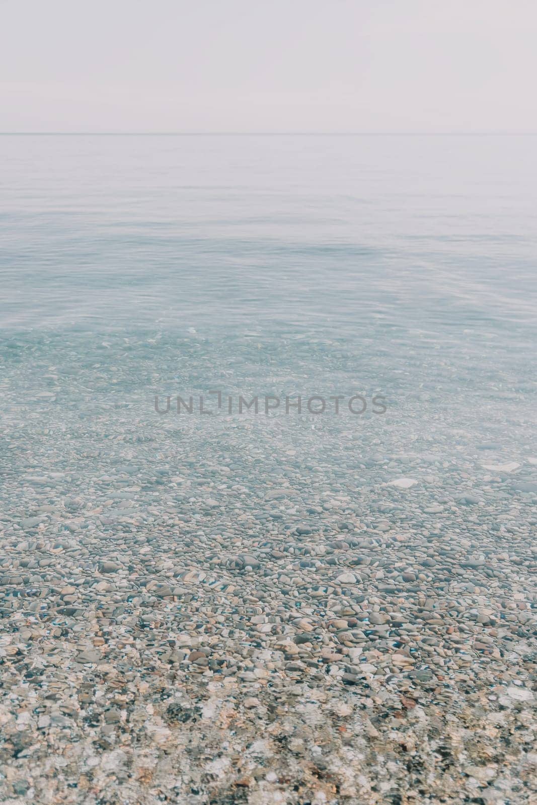 A calm body of water with a few rocks scattered throughout. The water appears to be clear and still, with no visible waves or ripples. The rocks are of various sizes