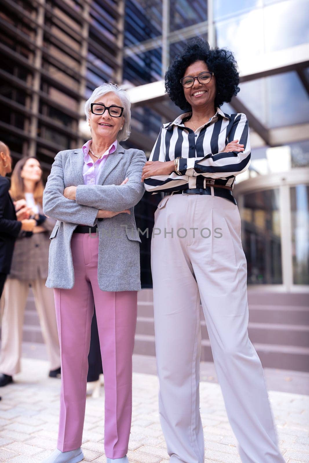 Happy businesswomen standing side by side with their arms crossed. Suitable for team, friendship and diversity concepts.