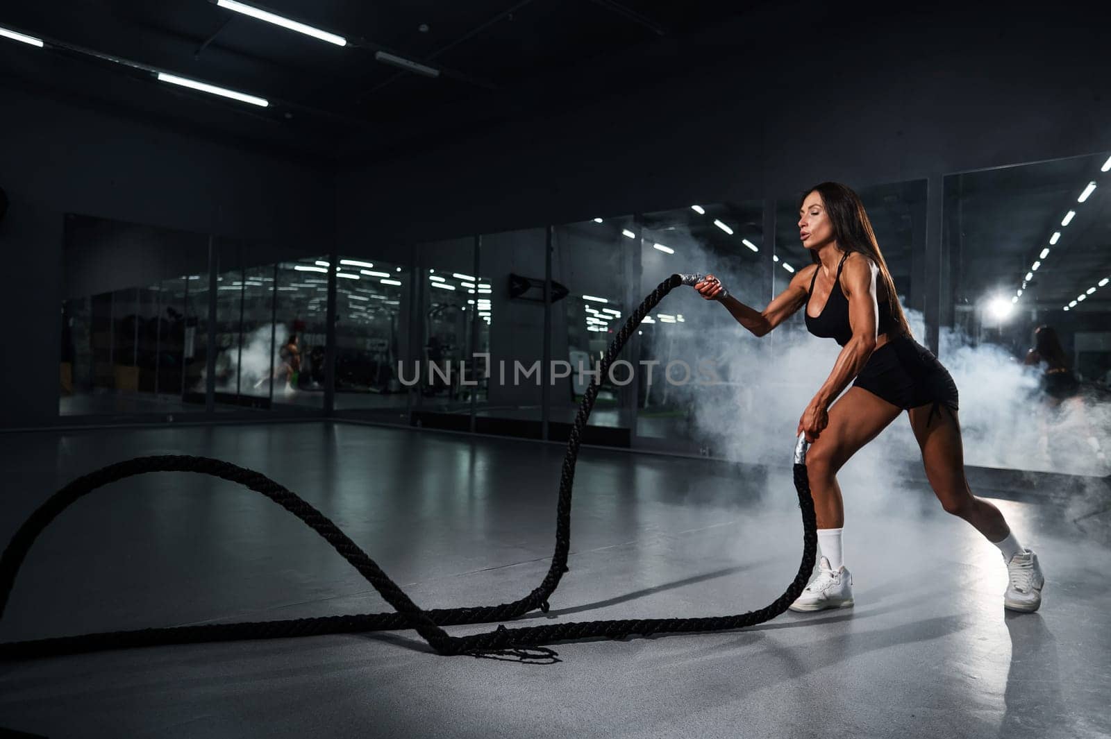 Caucasian woman doing exercise with ropes. Circuit training in the gym