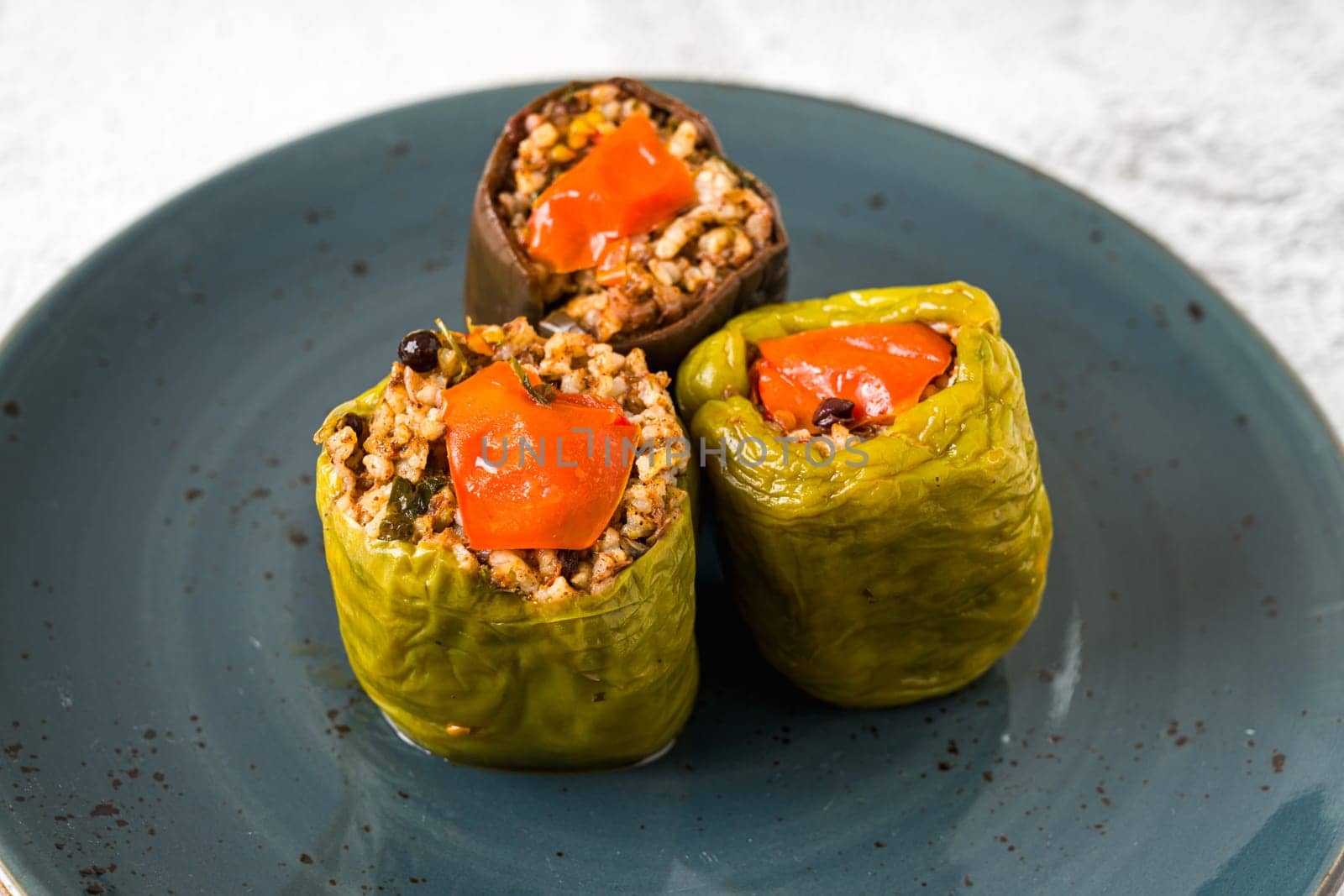 Stuffed green bell pepper and eggplant with olive oil on stone table by Sonat