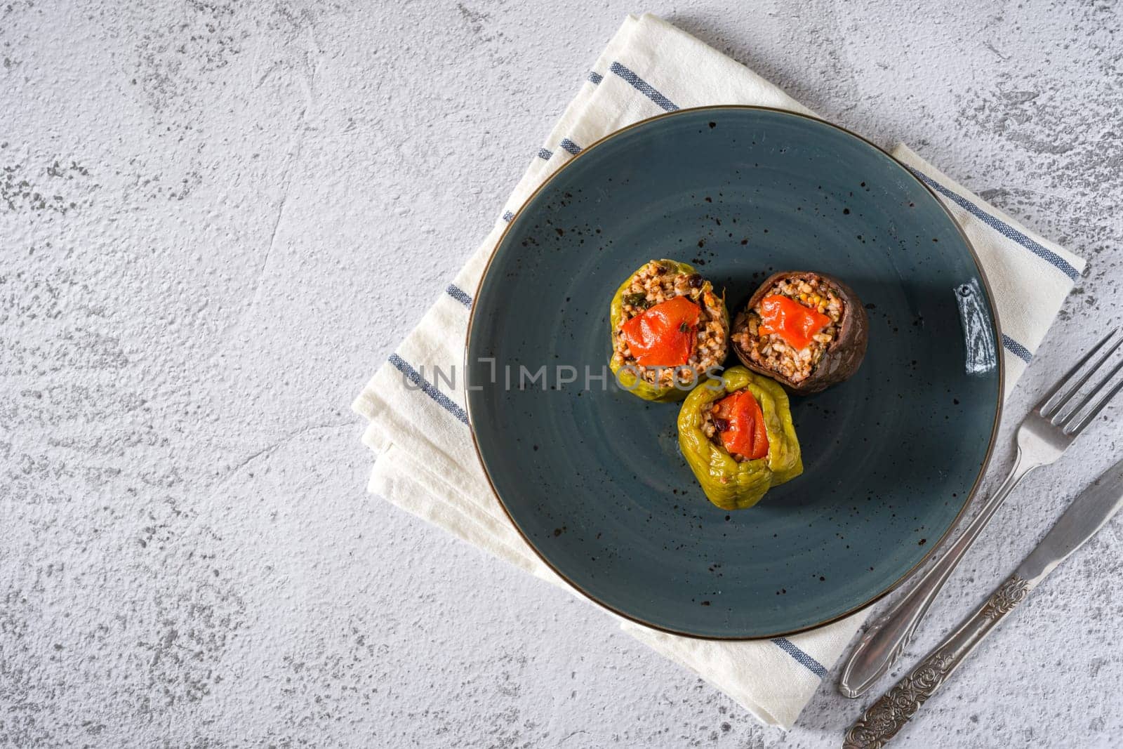 Stuffed green bell pepper and eggplant with olive oil on stone table