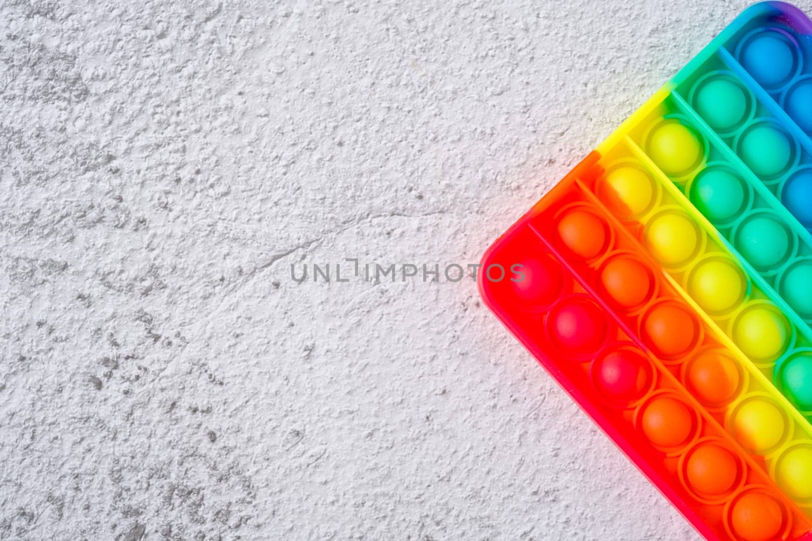 Top view of rainbow antistress sensory toy fidget push pop it on stone background