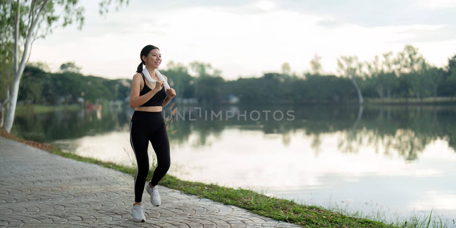 Woman running in the morning by a serene lake, promoting fitness, wellness, and a healthy lifestyle.