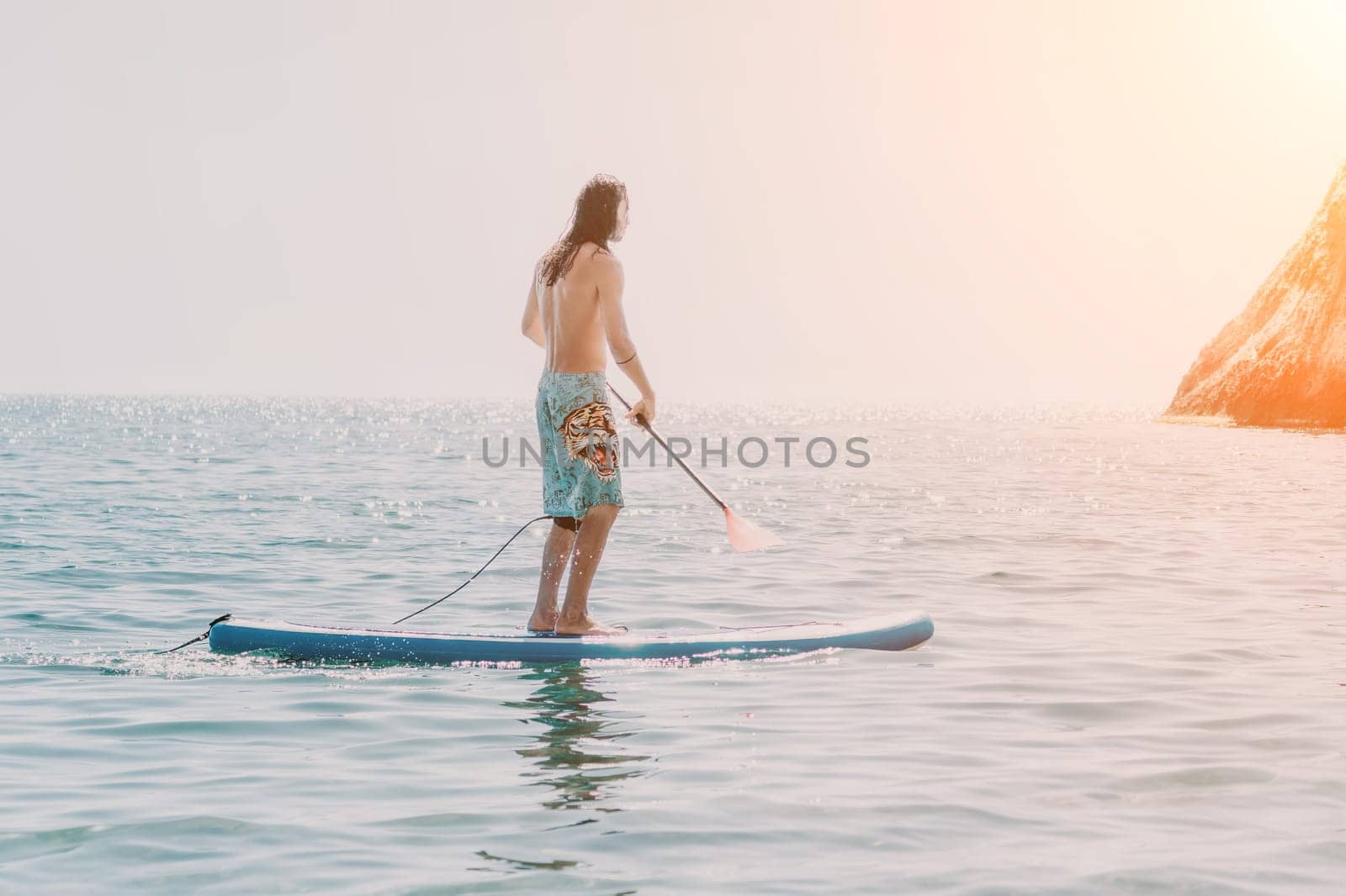 Man Sea Sup. Strong athletic man learns to paddle sup standing on board in open sea ocean on sunny day. Summer holiday vacation and travel concept. Aerial view. Slow motion.