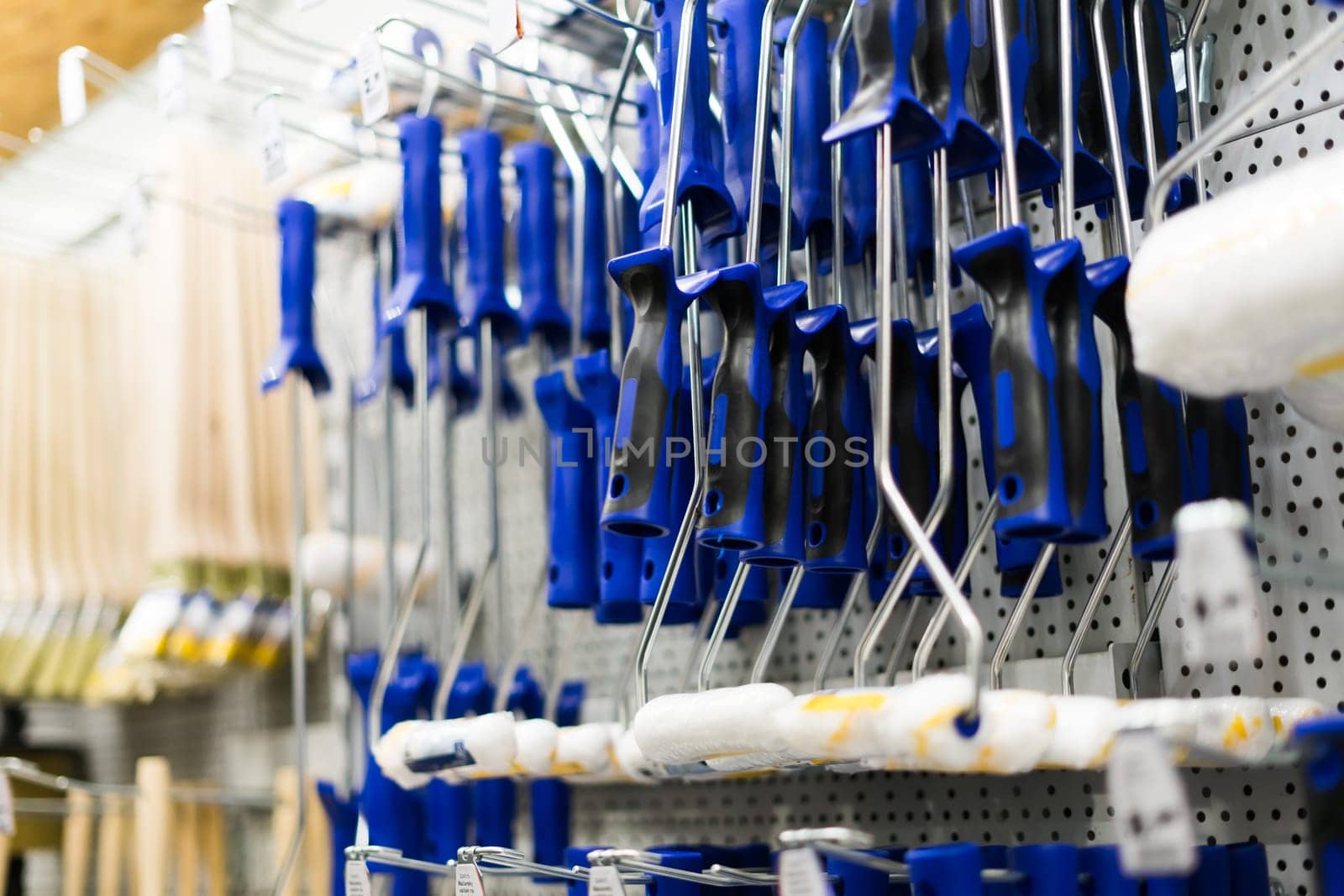 A store display of a paint brushes and rollers. The display is organized by color and size.