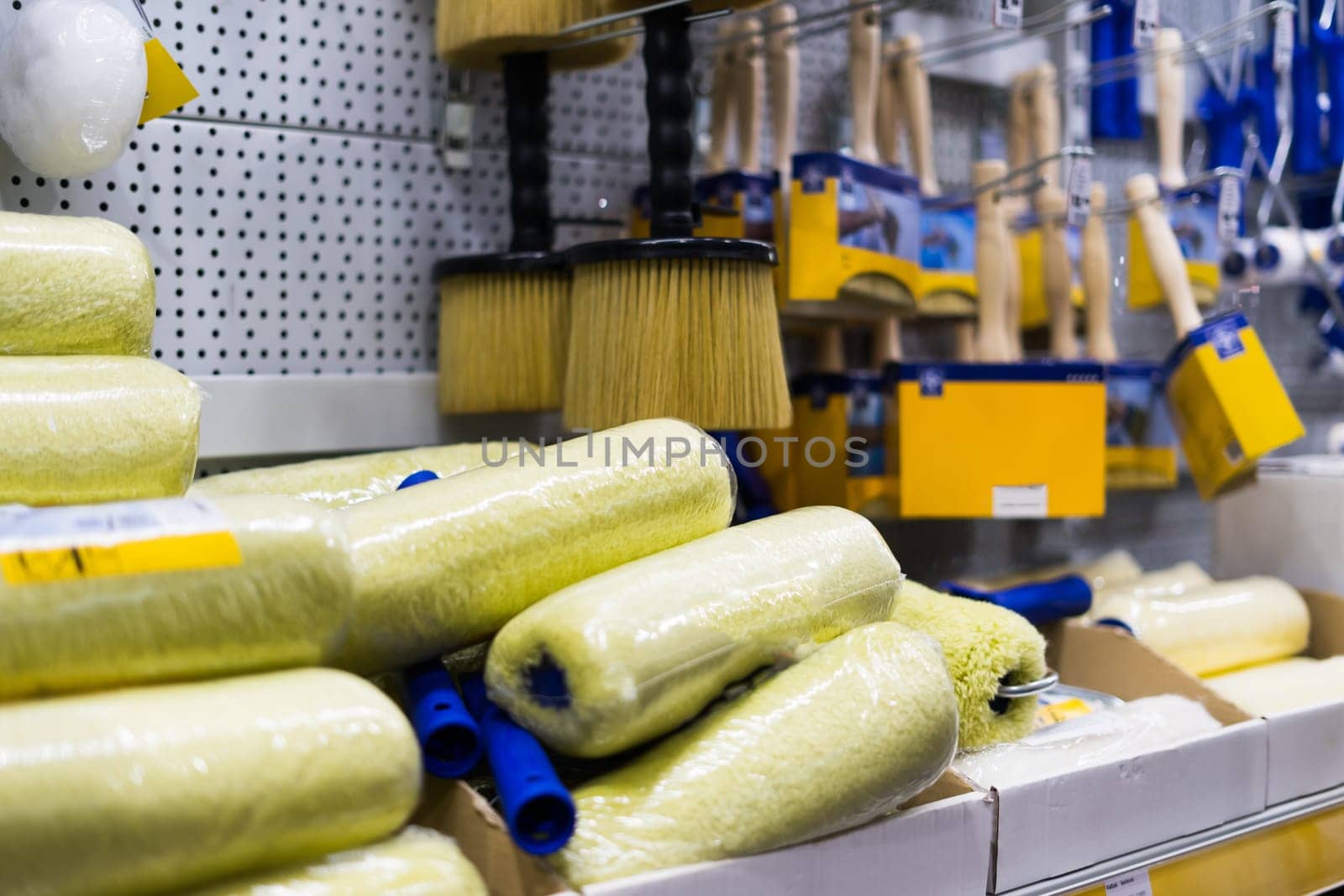 A store display of paint brushes and rollers. The display is organized by color and size. by Zelenin