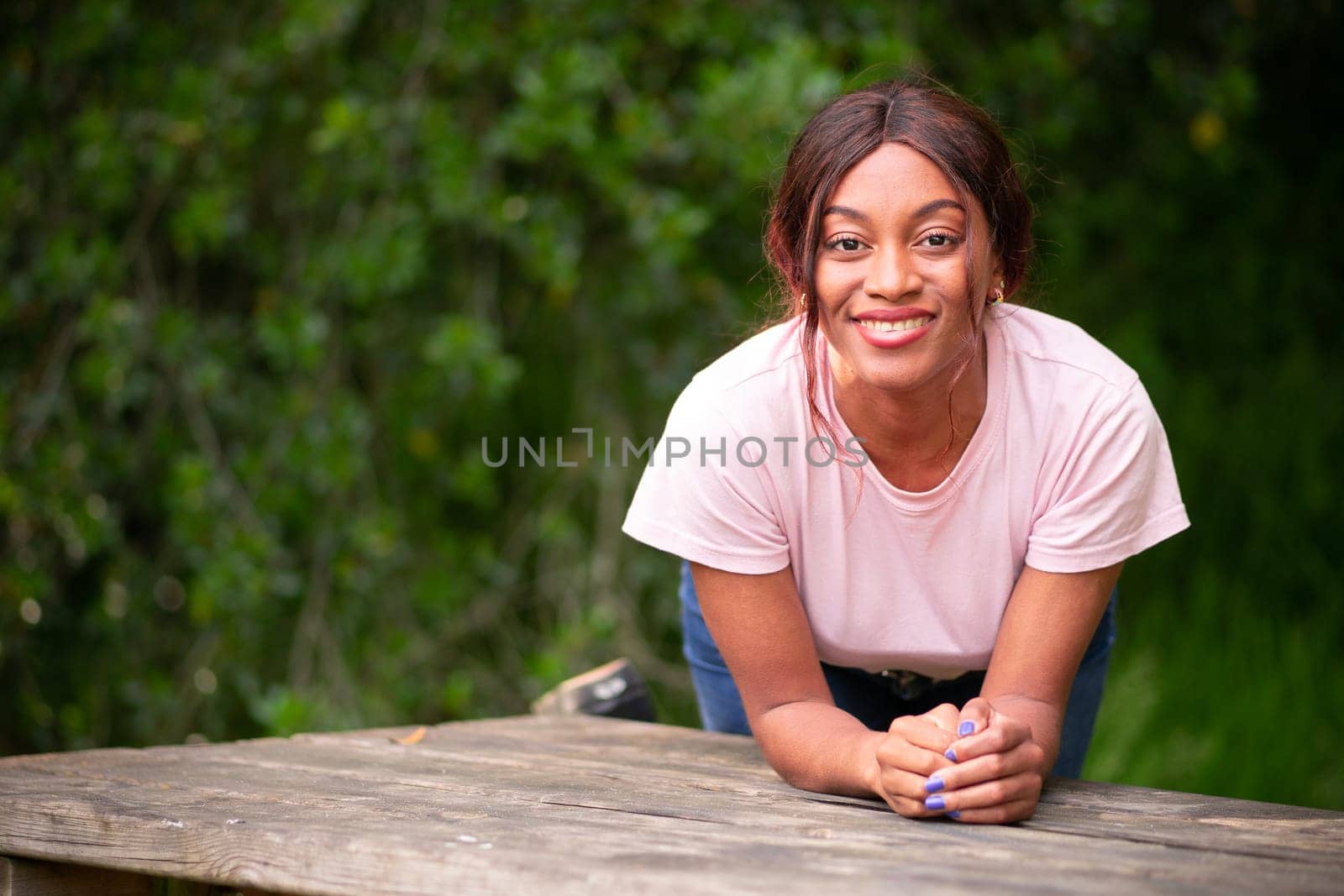 Young, beautiful black woman leaning on a bench in a park on an autumn afternoon.