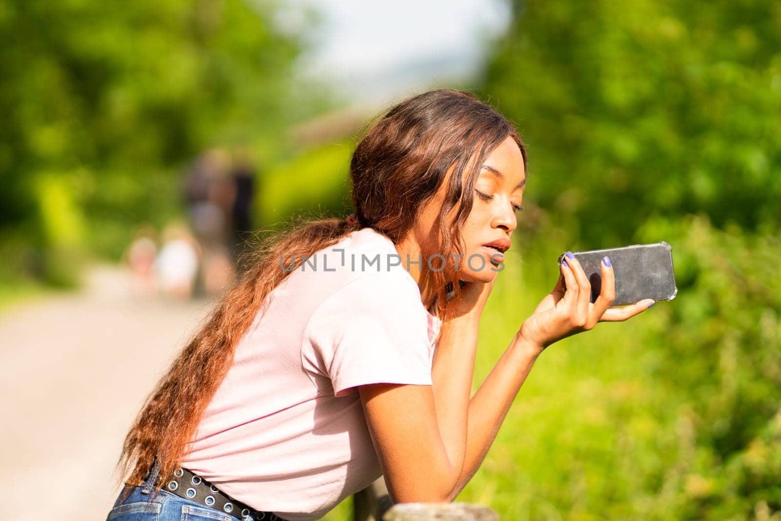Young black woman with her phone chatting with her friends in a park on an October afternoon.