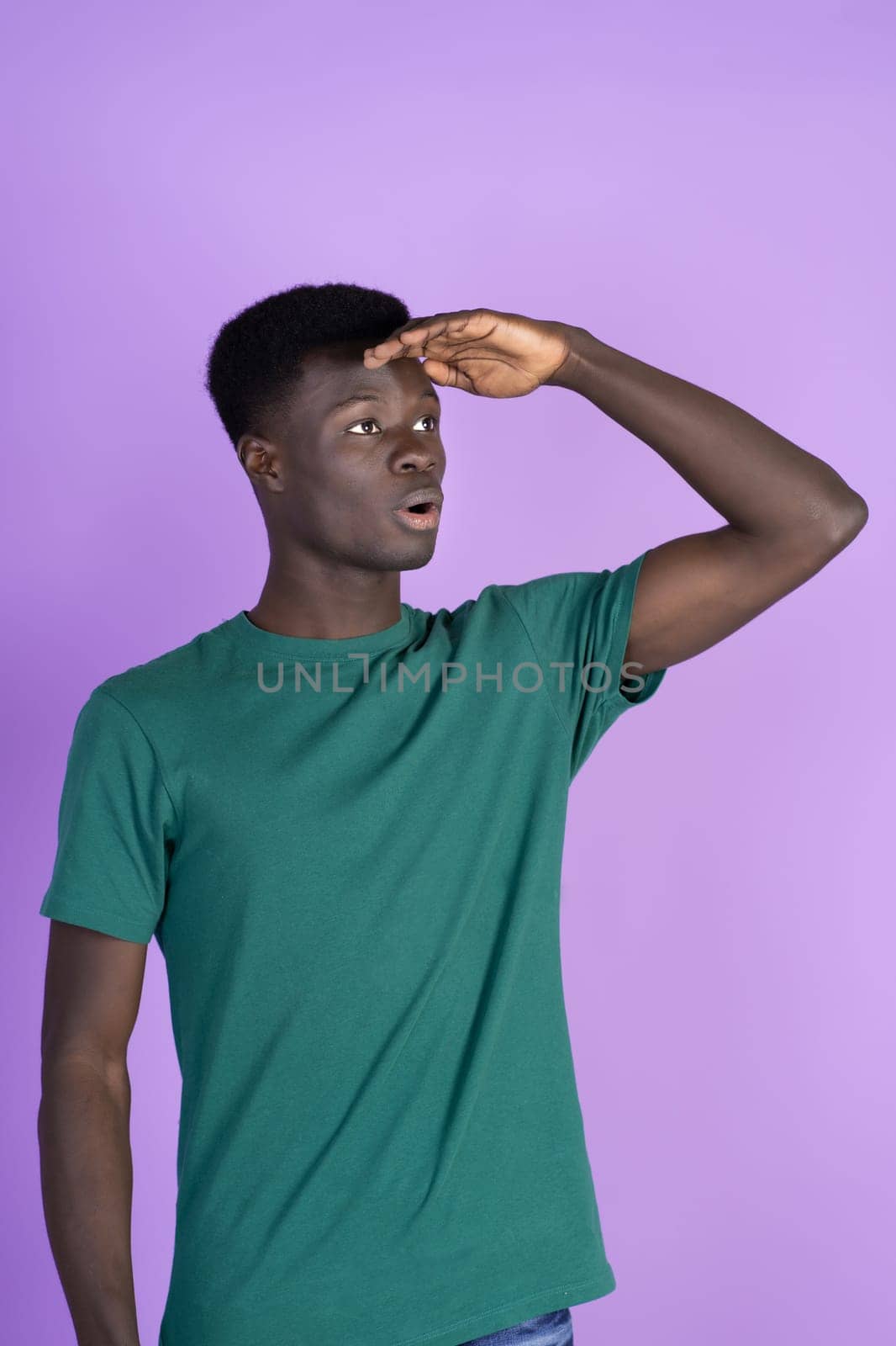 A man wearing a green shirt is shown holding his head with his hands.