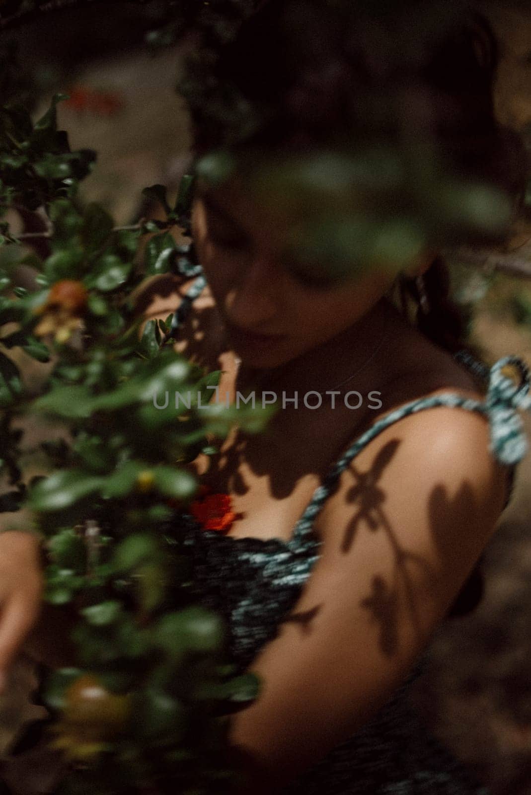 A young woman stands surrounded by lush green foliage, basking in the sunlight and embracing the beauty of nature