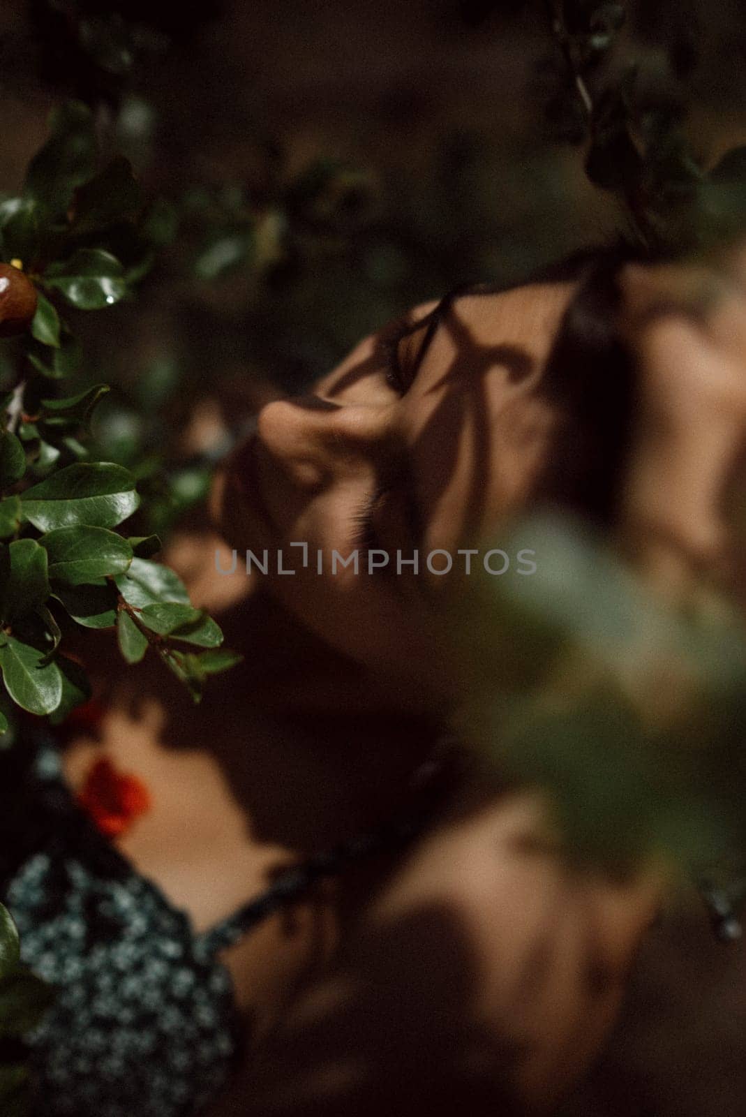 The photo features a serene woman surrounded by green foliage, creating a moody and intimate atmosphere in nature