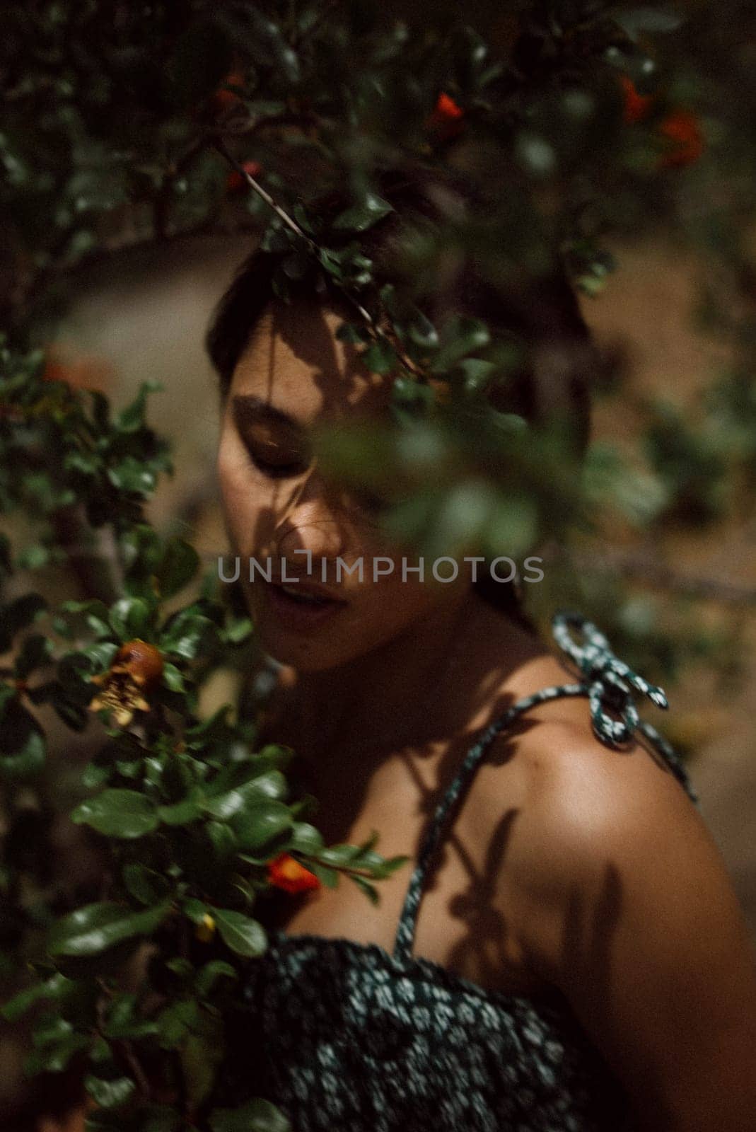 A woman merges with nature, surrounded by leaves and shadows, creating a mystical and dreamy ambiance