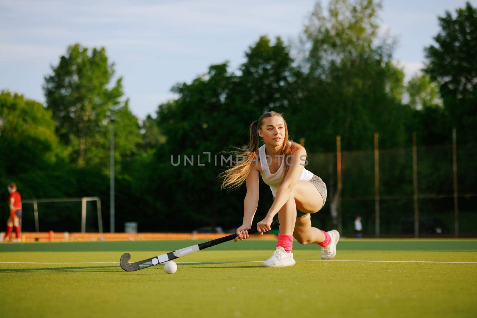 girl hockey player plays field hockey on a sunny day, female hockey player hits the ball with a stick, field hockey concept