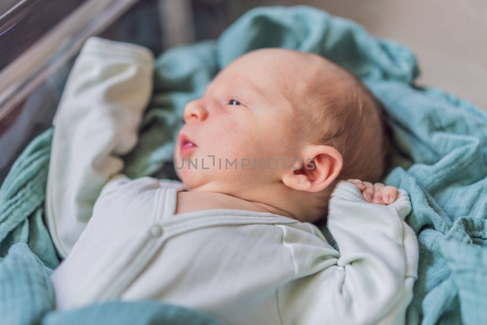 A newborn rests peacefully in his transparent bassinet in the hospital. The clear bassinet provides visibility for medical staff to monitor the baby's well-being while ensuring a safe and comfortable environment for the newborn.