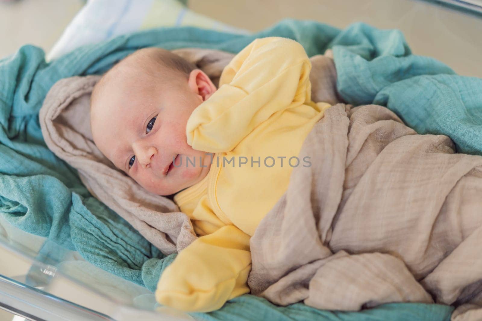 A newborn rests peacefully in his transparent bassinet in the hospital. The clear bassinet provides visibility for medical staff to monitor the baby's well-being while ensuring a safe and comfortable environment for the newborn.